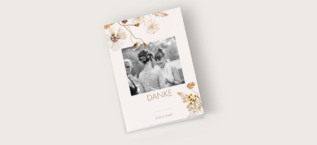 Ein wunderschönes CEWE Fotobuch mit dem Titel "DANKE" und einem romantischen Design. Es zeigt eine Schwarzweißaufnahme von drei Frauen mit festlichem Haarstyling, umgeben von zarten floralen Elementen und goldenen Akzenten.