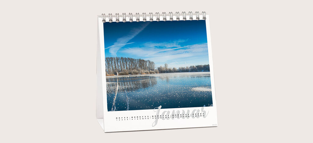 Kalenderblatt für Januar mit schöner Winterlandschaft: gefrorener See, Bäume im Hintergrund und blauer Himmel