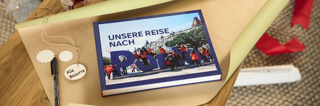 Geschlossenes CEWE FOTOBUCH mit dem Titel Unsere Reise nach Porto auf Geschenkpapier.