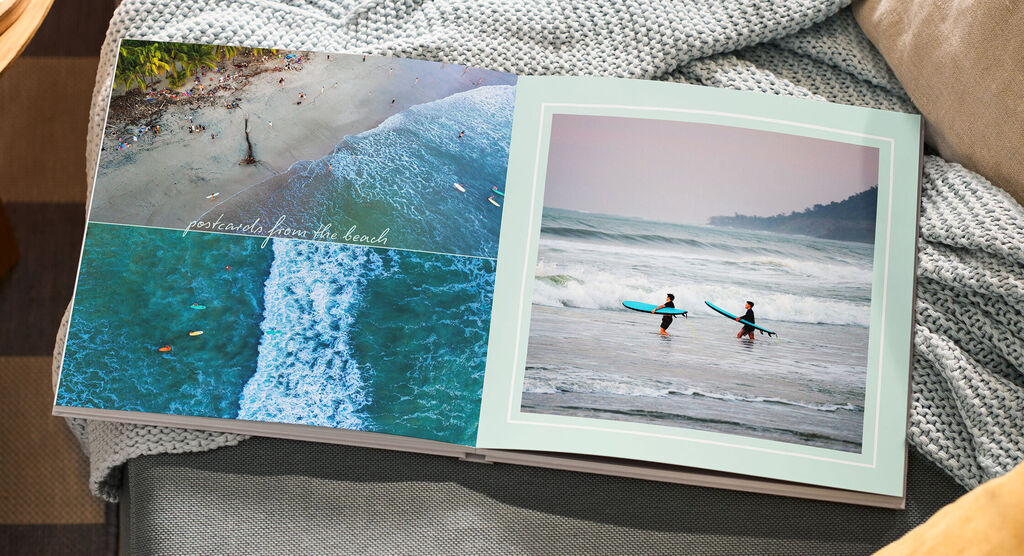 CEWE FOTOBUCH Seite: Strand aus der Luft, Wellen und zwei Personen mit Surfbrett; Text: postcards from the beach
