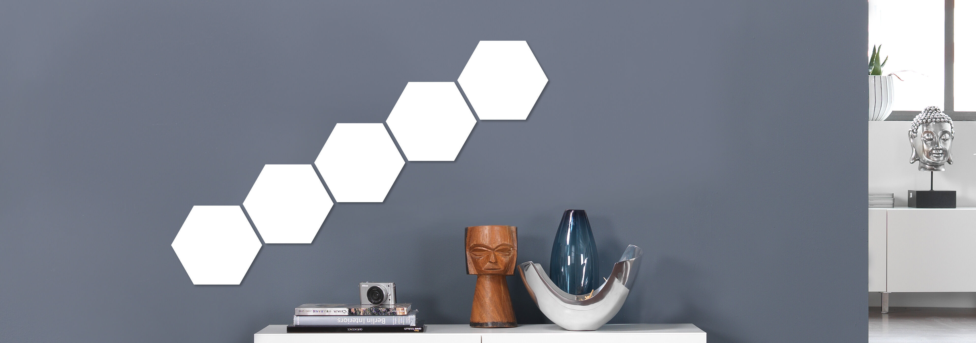 Moderne Wandgestaltung mit weißen sechseckigen Formen und dekorativen Objekten auf einem Tisch.