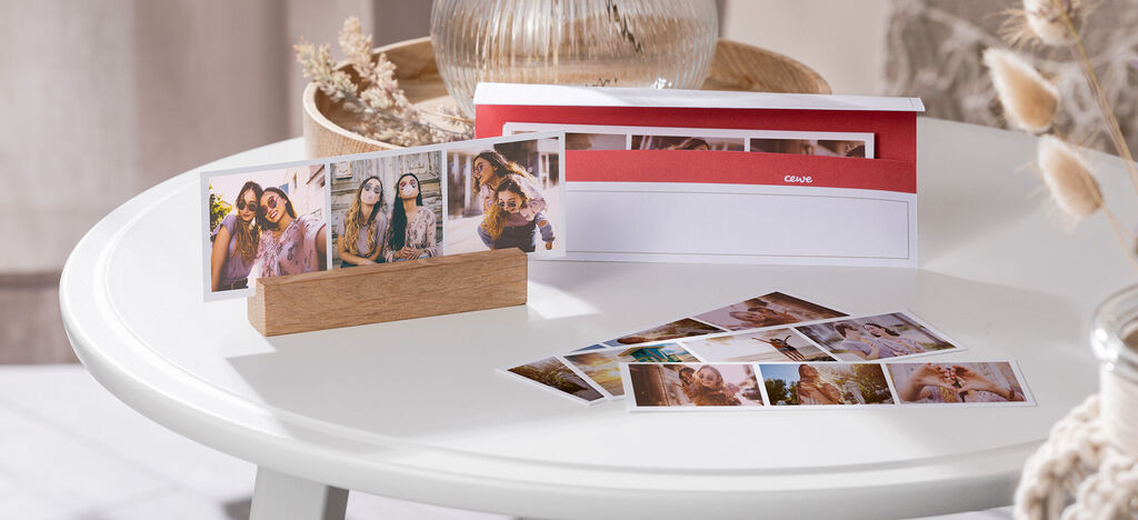 Ein frohes Bild mit CEWE Fotobuch und Fotos auf einem Tisch, das schöne Erinnerungen zeigt