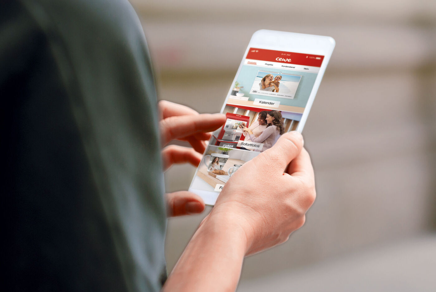 Person hält ein Smartphone und schaut auf die CEWE App.