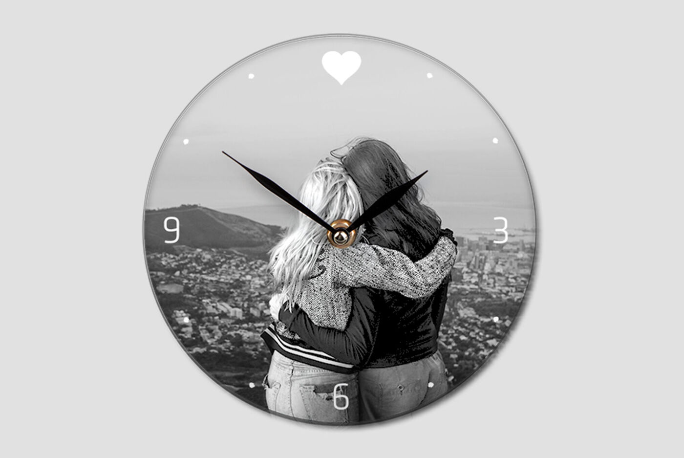 Zwei Frauen umarmen sich lächelnd vor einer Stadtlandschaft auf einer Wanduhr.