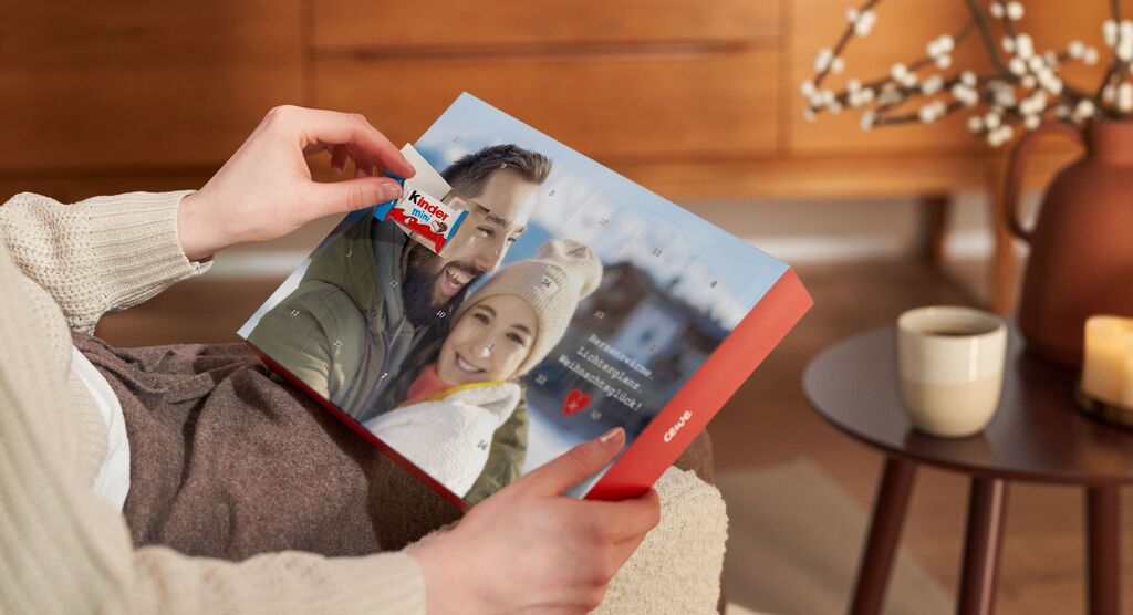 eine Person hält ein CEWE FOTOBUCH in der Hand, auf dem ein glückliches Paar abgebildet ist