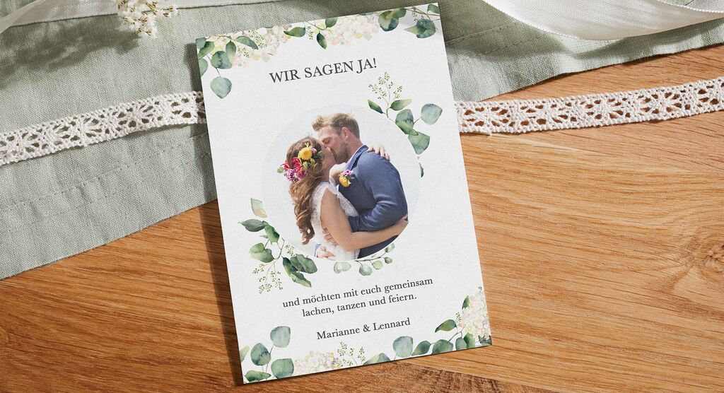 Elegantes Einladungsdesign für eine Hochzeitsfeier, mit dem Text 'Wir sagen Ja!' und einem romantischen Brautpaar im Vordergrund