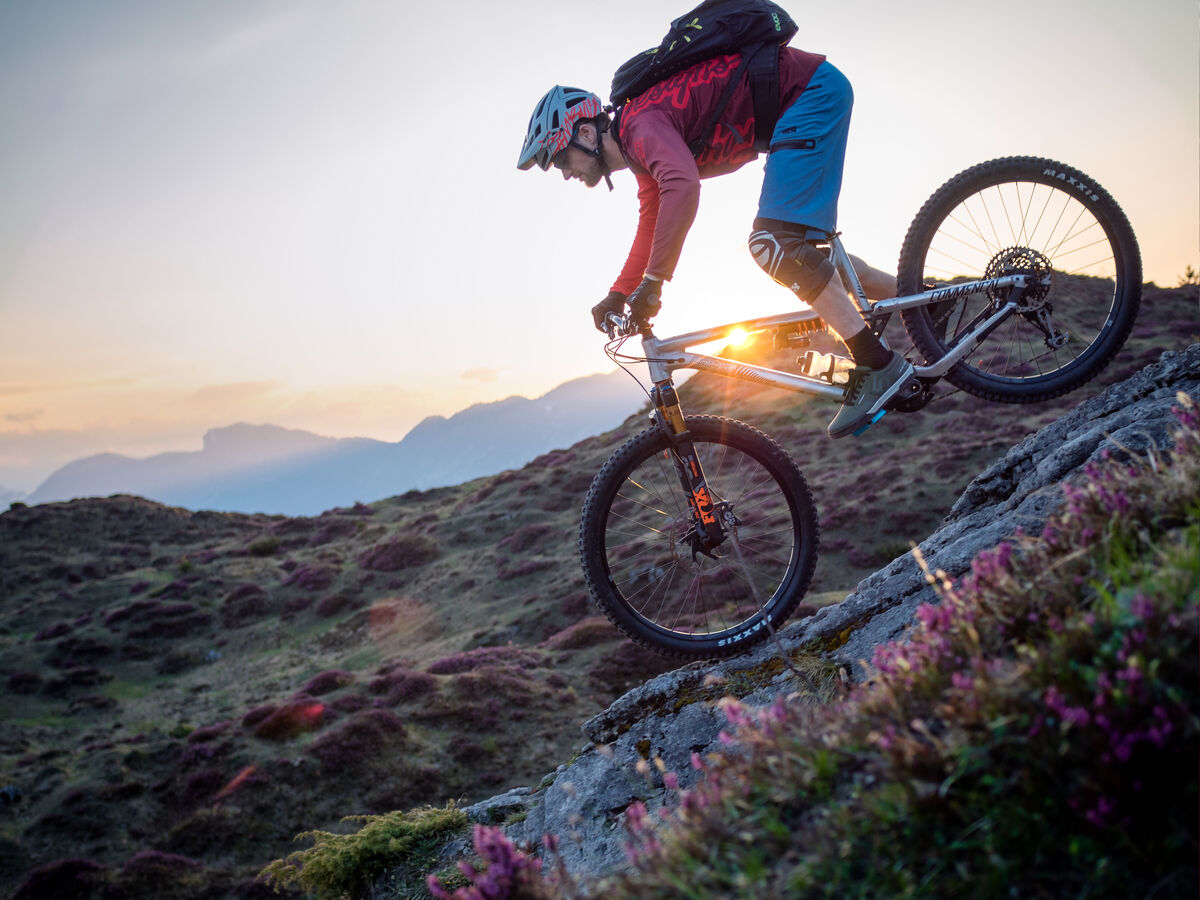 Ein Mountainbiker fährt auf einem steilen Felsen in der Natur.