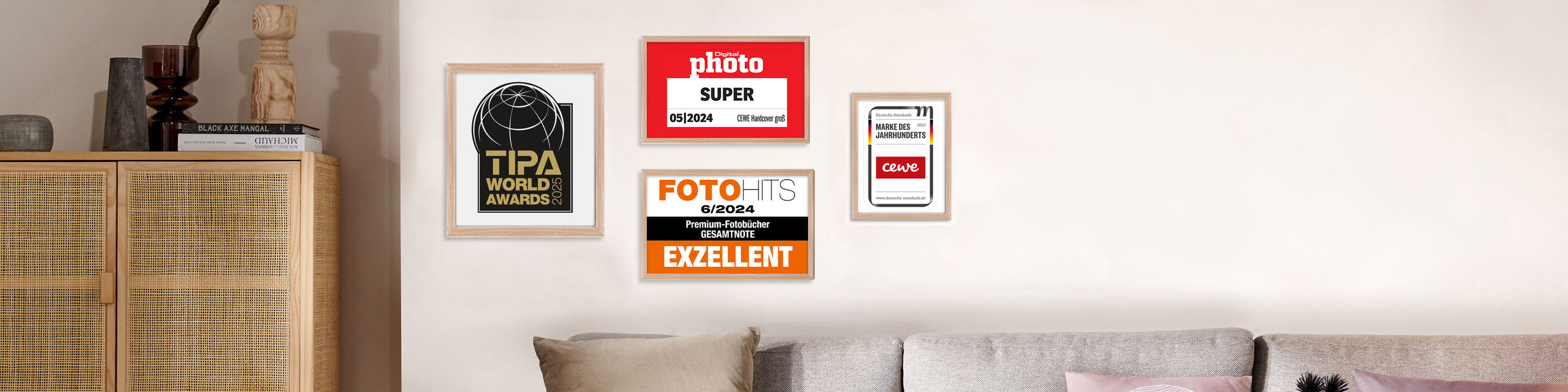 Wanddekoration mit verschiedenen Auszeichnungen und Zertifikaten an einer Wand über einem hellen Sofa arrangiert