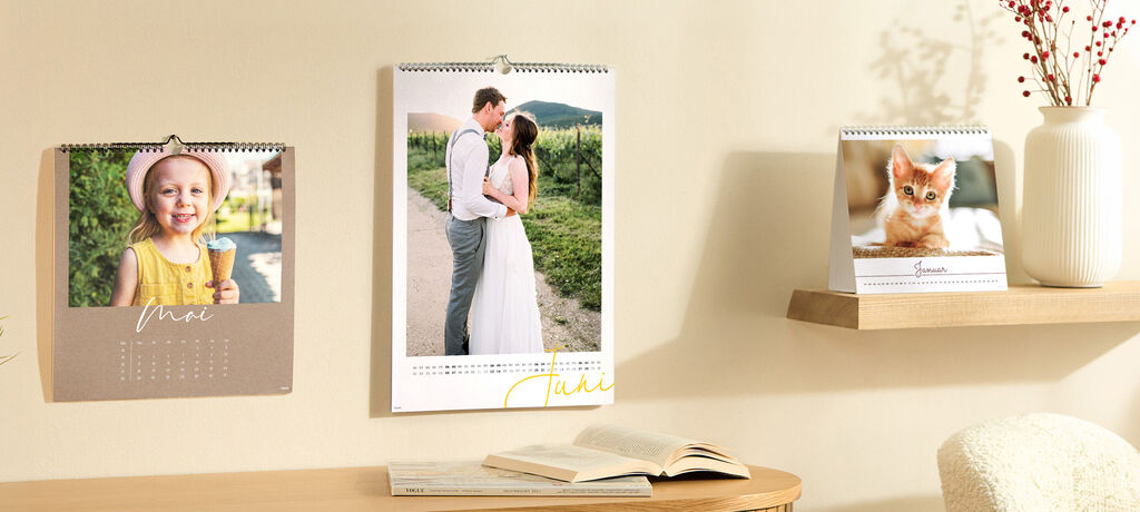 An einer Wand hängen drei Kalender. Sie sind mit Fotos gestaltet.