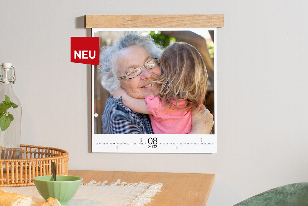 Ein kalendarisches Wandbild zeigt einen Monat mit liebevollem Bild einer Person und einem Kind in einer Umarmung