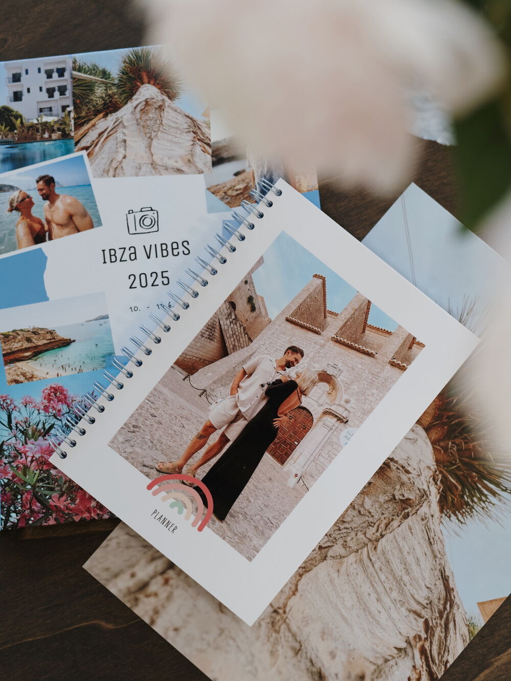 Ein Fotobuch mit Urlaubsbildern, darunter ein Paar vor einem historischen Gebäude, umgeben von Fotos und einer Kalenderseite.