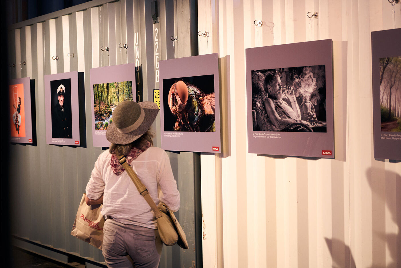 Besucher betrachtet kreative Fotografien an einer Wand