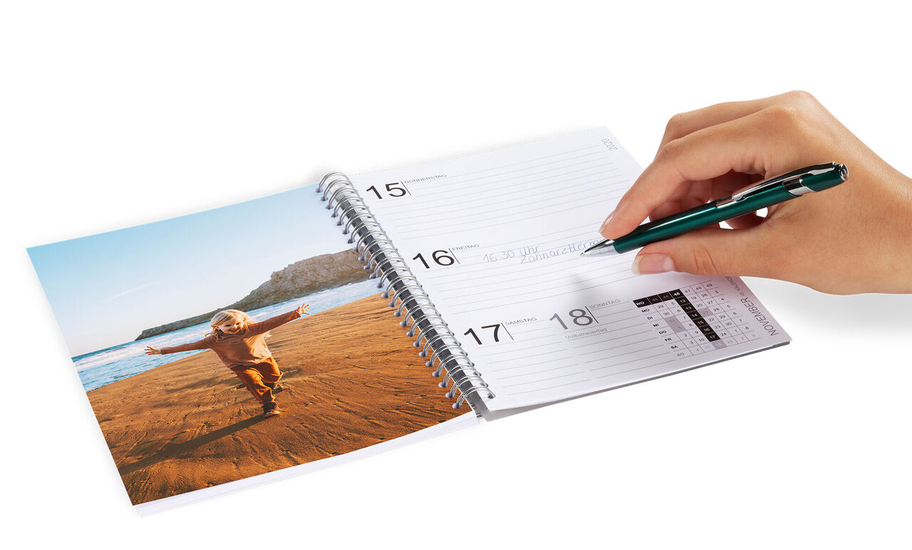 Ein Kind spielt glücklich am Strand, während eine Hand einen Kalender beschriftet