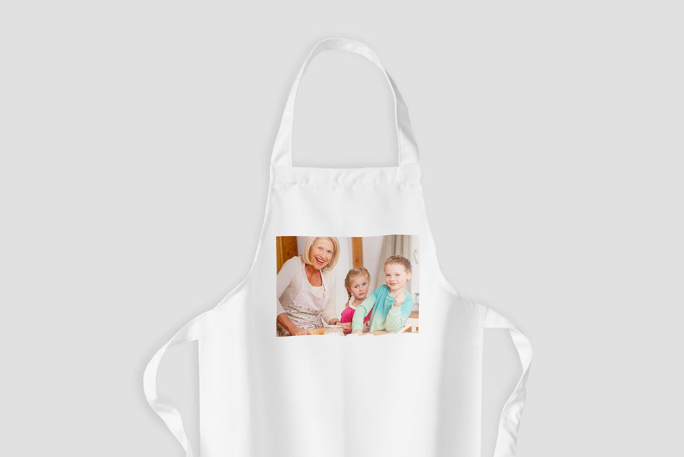 Ein weißer Schürze mit einem Bild von zwei lächelnden Kindern. Die Schürze symbolisiert kreative Kochmomente.