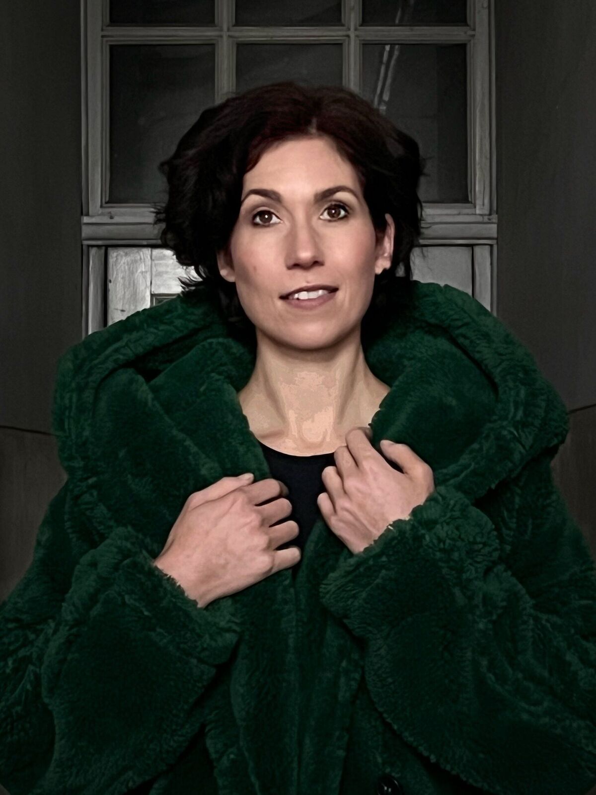 Junge Frau in grüner fester Jacke, die ihr Gesicht lächelnd zur Seite neigt