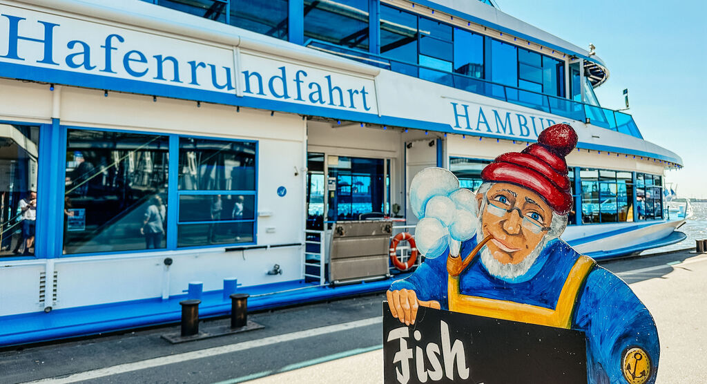 Weißes Rundfahrt-Schiff im Hafen mit Hamburger Schriftzug, sonniger Tag
