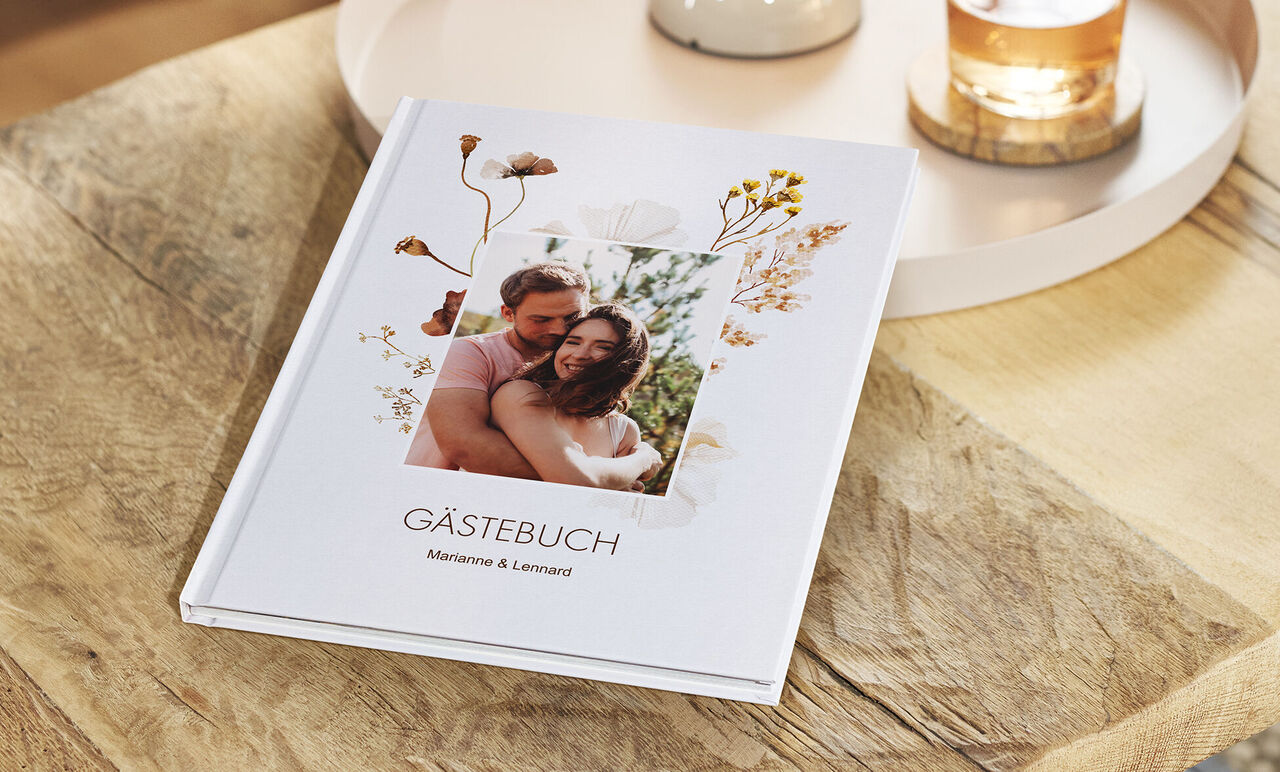 Ein schön gestaltetes Gästebuch mit floralen Elementen auf einem Holztisch