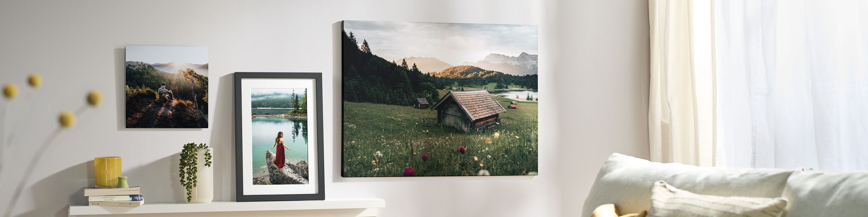 Drei CEWE Wandbilder mit Naturmotiven und Menschen über einem weißen Regal an einer hellen Wohnzimmerwand