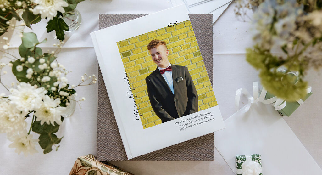 Ein schön gestaltetes CEWE Fotobuch liegt auf einem Tisch, umgeben von Blumen und Geschenken.