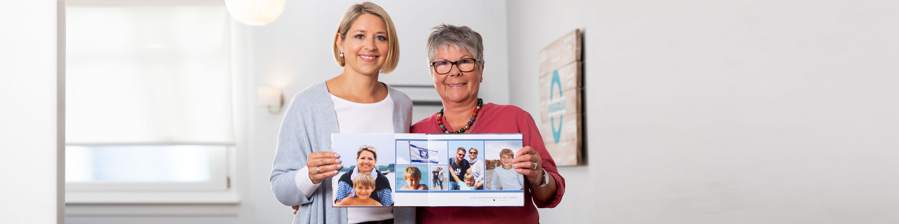 Zwei Personen halten mit Freude ein Fotobuch. Es zeigt Glücksmomente und Erinnerungen.