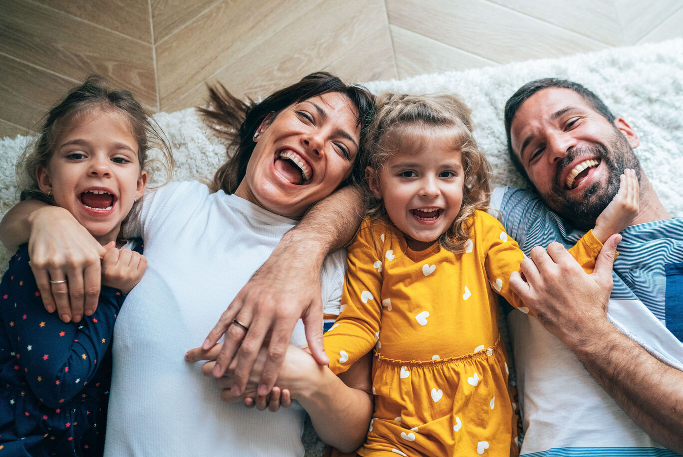 Familie liegt glücklich auf dem Boden und hält sich an den Händen