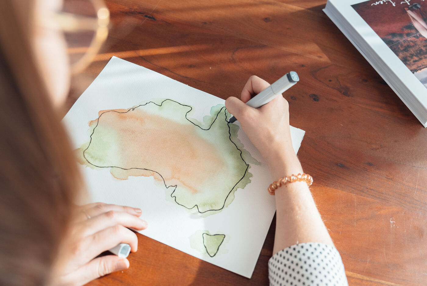 Eine Person zeichnet eine Karte von Australien mit Aquarellfarben.