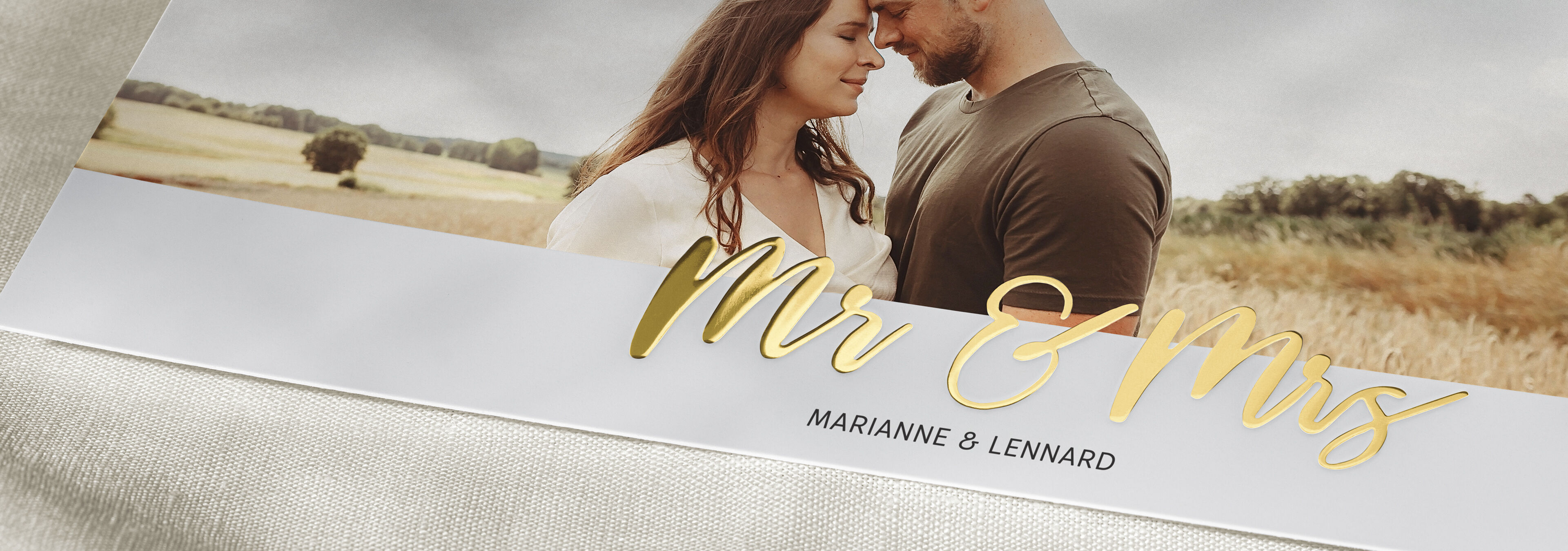 Ein glückliches Paar steht in einer schönen Landschaft mit goldenen Schriftzug "Mr & Mrs".