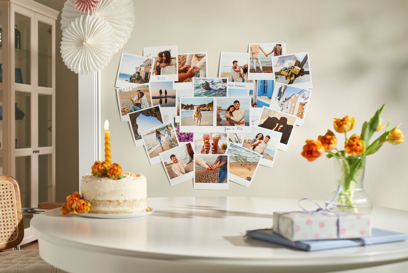 Eine hübsche Tischdekoration mit Fotografien in Herzform auf einem Tisch, umgeben von einer Torte und Blumen.
