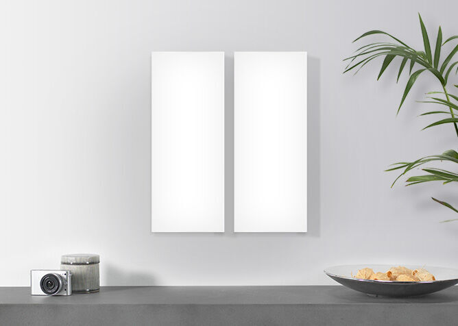 Zwei leere weiße Rahmen an einer Wand, Pflanzen und Dekorationsteller im Hintergrund