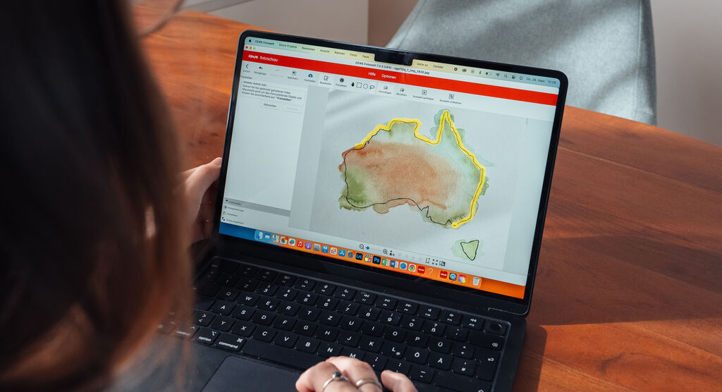 Frau arbeitet am Laptop und bearbeitet eine Karte von Australien