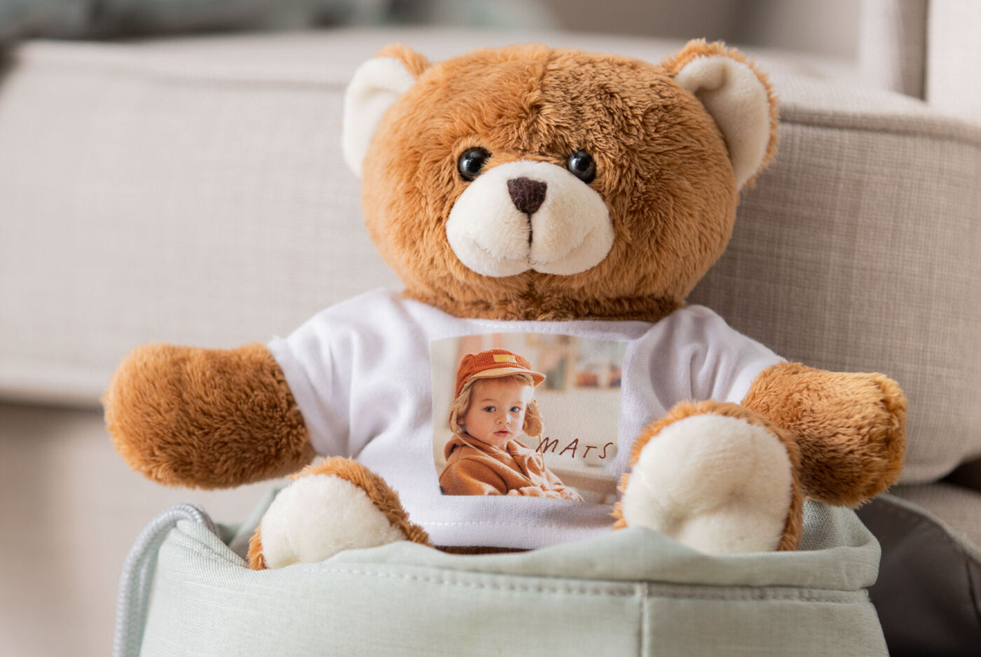 Sitzender brauner Teddybär mit weißem T-Shirt und Fotomotiv.