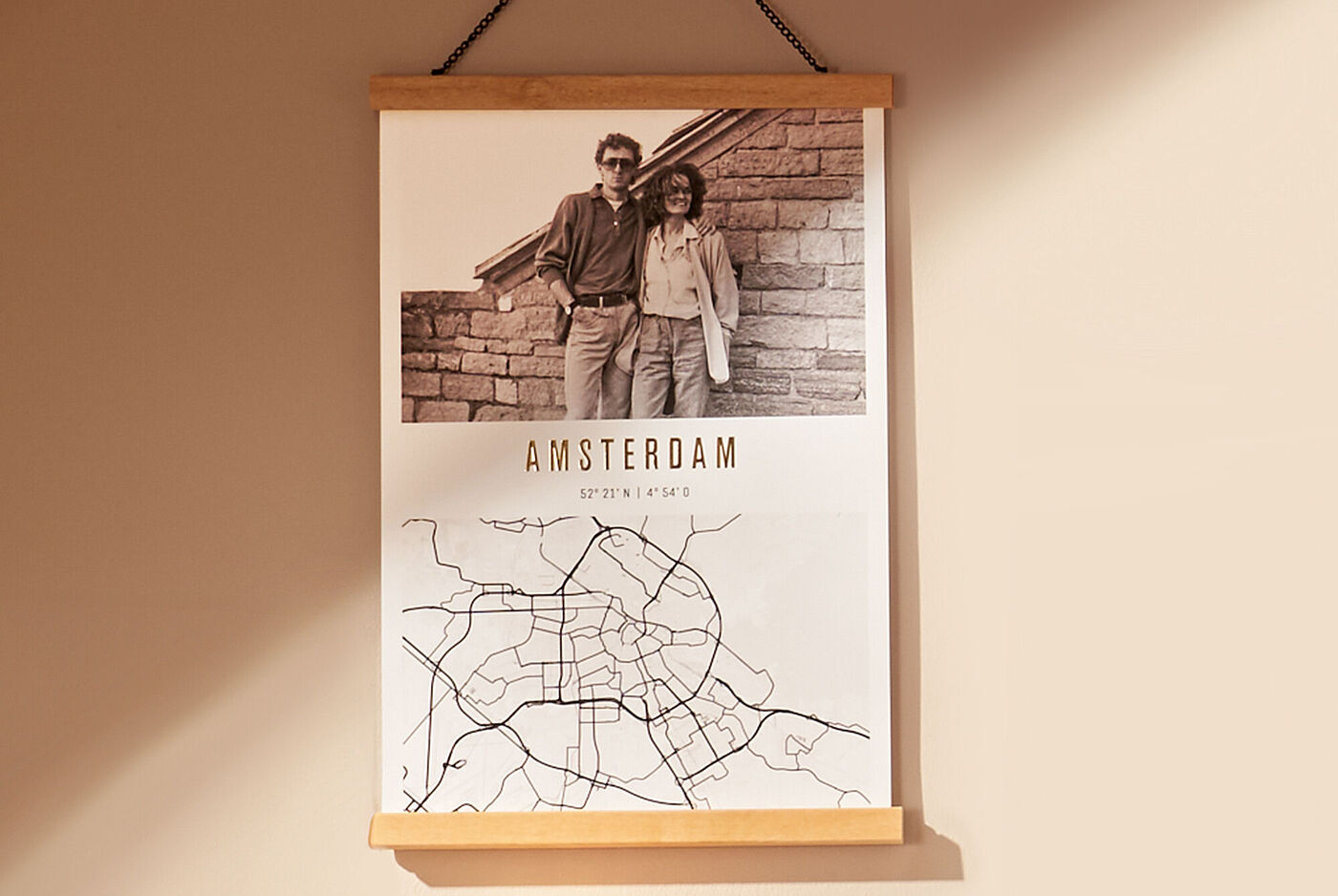 Ein Wandbild zeigt eine Schwarz-Weiß-Fotografie eines Paares vor einer gemauerten Wand, mit einer Karte von Amsterdam darunter.