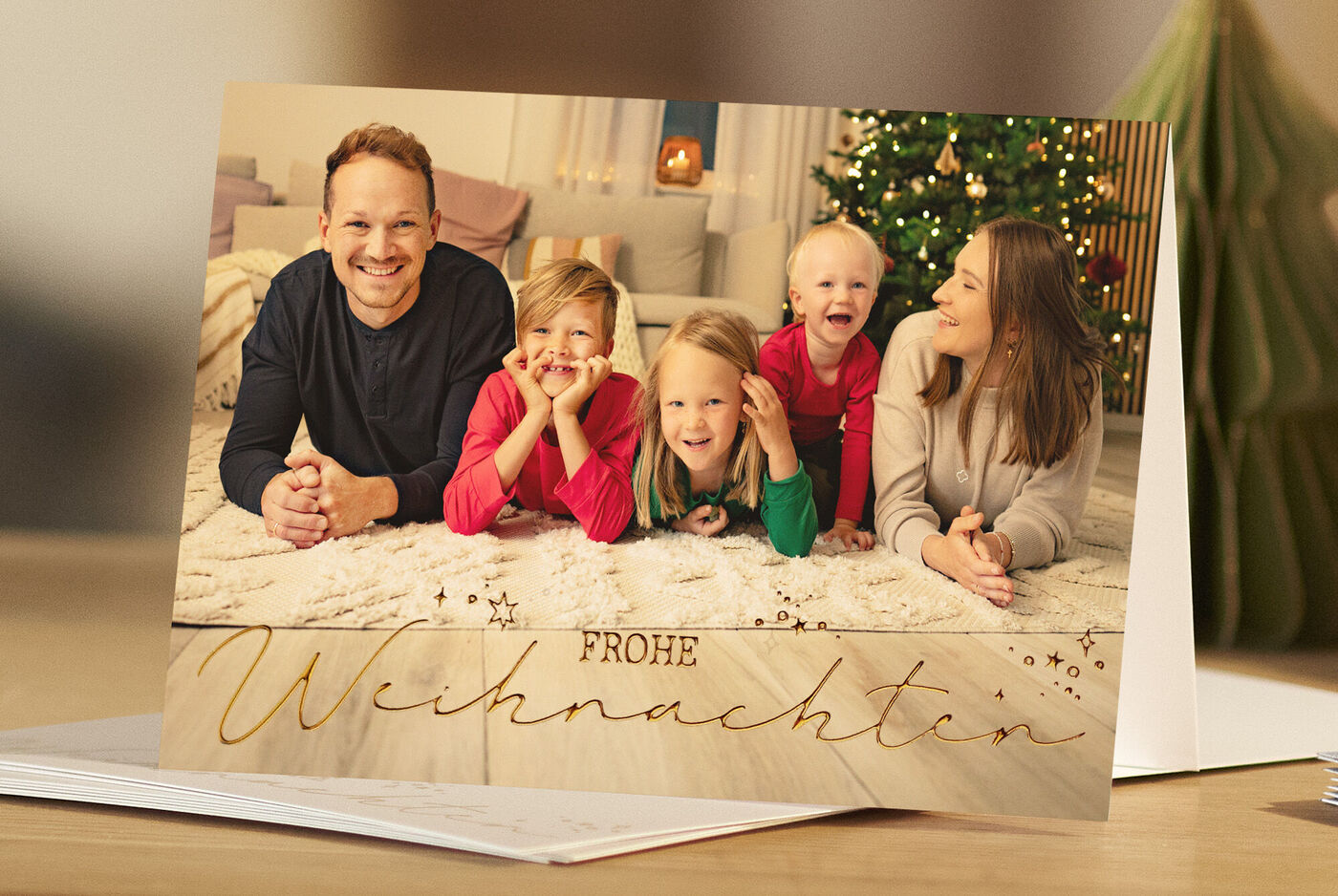 Familie sitzt auf dem Boden und feiert Weihnachten in einem festlich geschmückten Raum