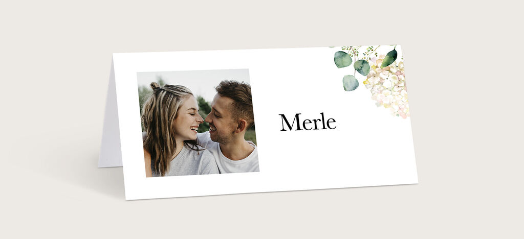 Ein personalisierter Tischaufsteller mit dem Namen Merle, dekoriert mit floralen Akzenten