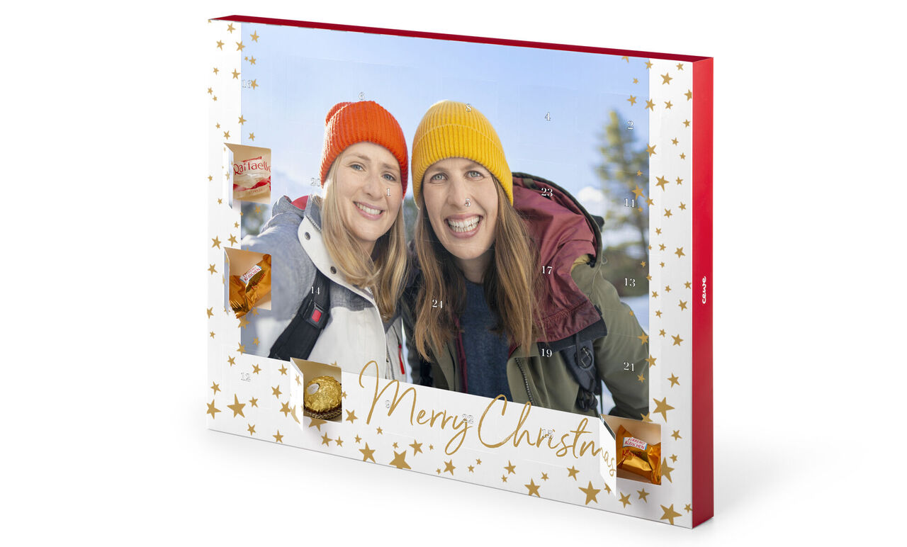 Bunte Weihnachtsmütze tragende Personen stehen in einem Winterwald vor einem Weihnachtskalender. Auf der rechten Seite ist ein grüner Hinweis, dass es aus nachwachsenden Rohstoffen besteht.