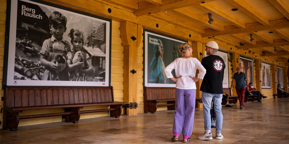 Ein Mann und eine Frau betrachten Fotos in einer großen Ausstellung.