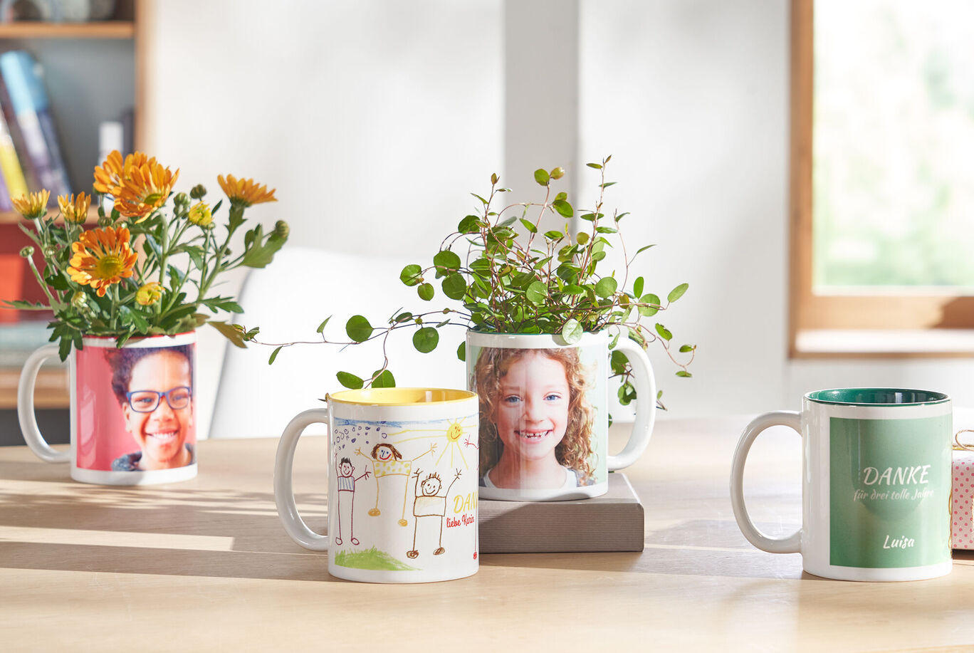 Vier individuelle Tassen mit Blumen, die auf einem Tisch stehen