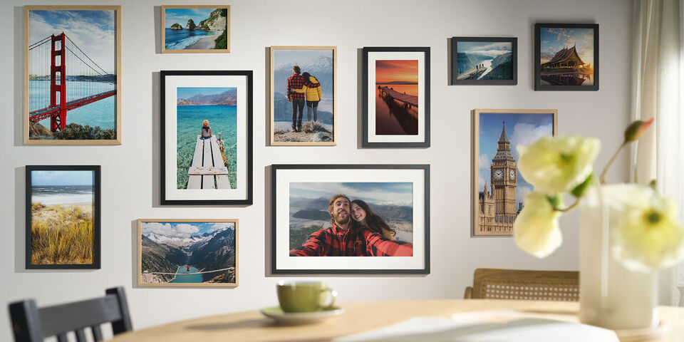 Bunte CEWE Wandbilder mit Reiseerlebnissen und Lieblingsorten in eleganten Rahmen über einem Esstisch