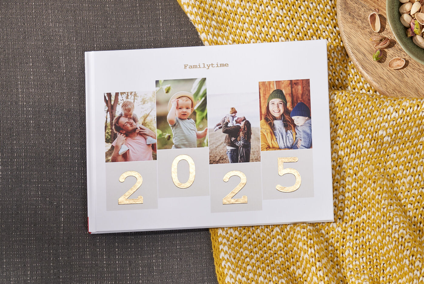 Ein CEWE FOTOBUCH mit Fotos von glücklichen Familienmomenten und der Jahreszahl 2024.