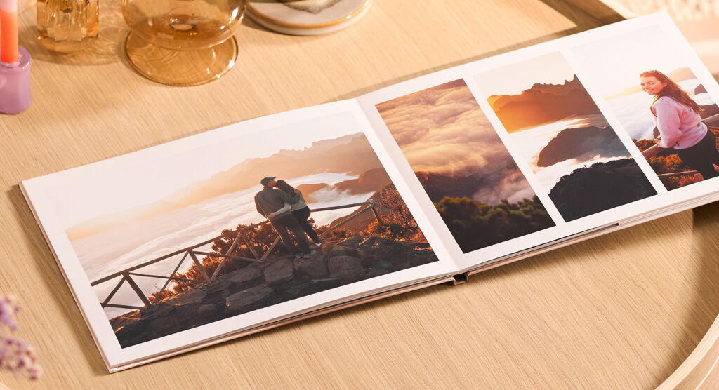 CEWE FOTOBUCH mit Urlaubsfotos bei Sonnenaufgang auf Holztisch