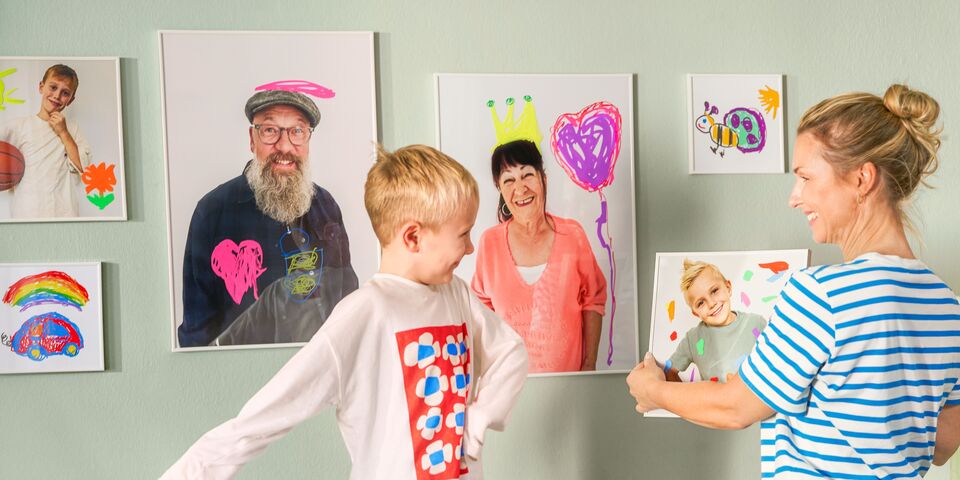 Kind und Erwachsene gestalten liebevoll bemalte Poster und Bilderrahmen in einem kreativ eingerichteten Raum