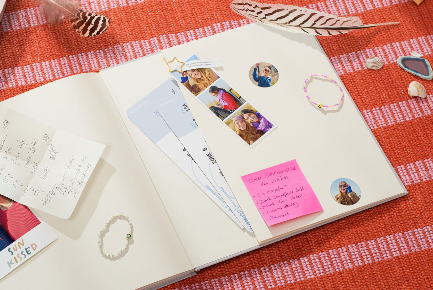 Offenes Scrapbook mit eingeklebten Fotos, Eintrittskarten, Notizzetteln und kleinen Erinnerungsstücken auf einer gestreiften Unterlage.