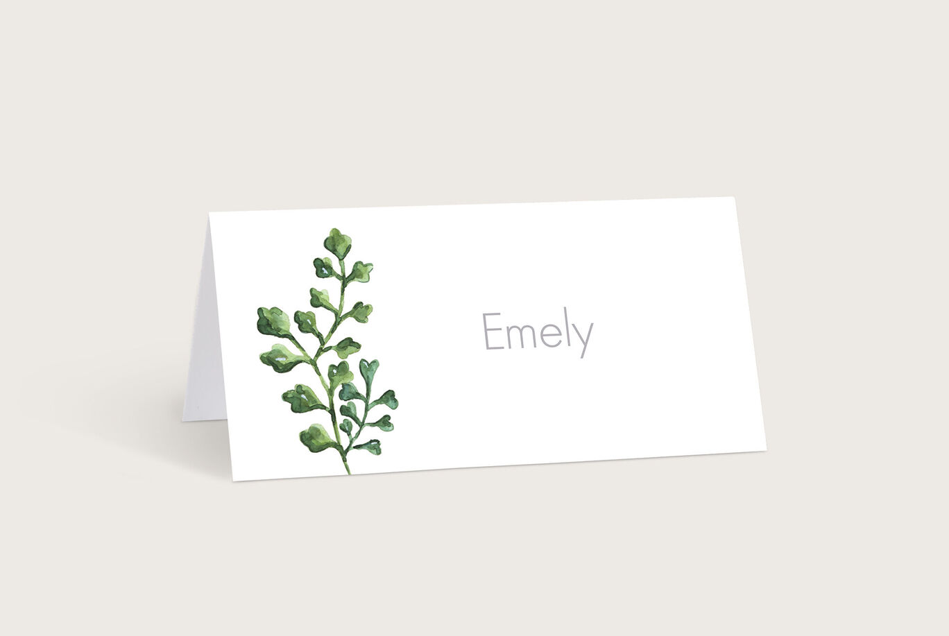 Eine liebevoll gestaltete Tischkarte mit einem grünen Blattmotiv und dem Namen Emely in schlichtem Grau