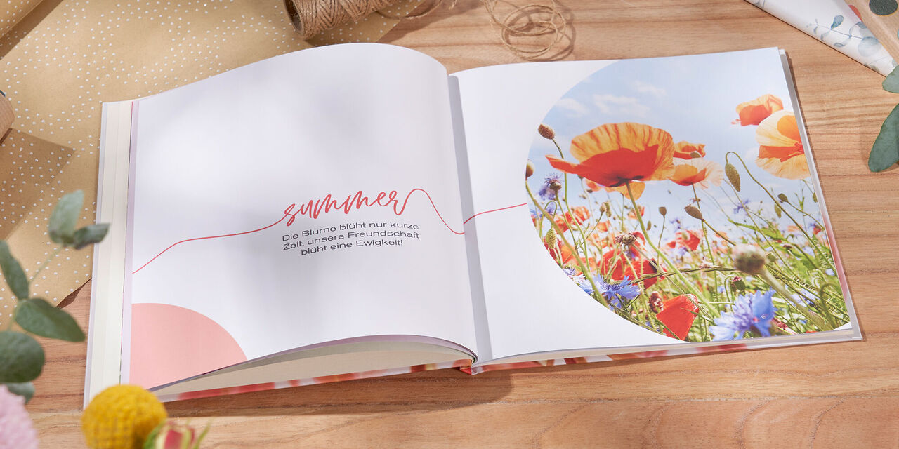 Das offene CEWE Fotobuch zeigt bunte Blumen auf einer Seite, mit einer herzlichen Überschrift ‘Sommer’.
