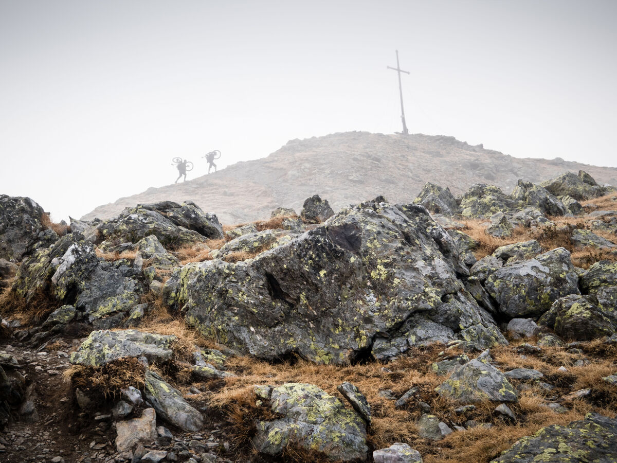Wanderer auf einem mystischen Berg mit einem Kreuz im Nebel