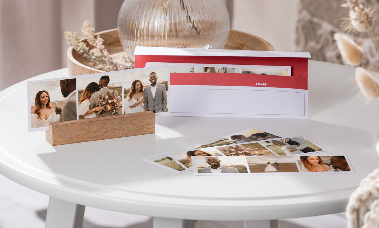 Ein stilvoll präsentierter CEWE Fotokalender auf einem Tisch mit Fotos einer Hochzeit und romantischen Momenten.