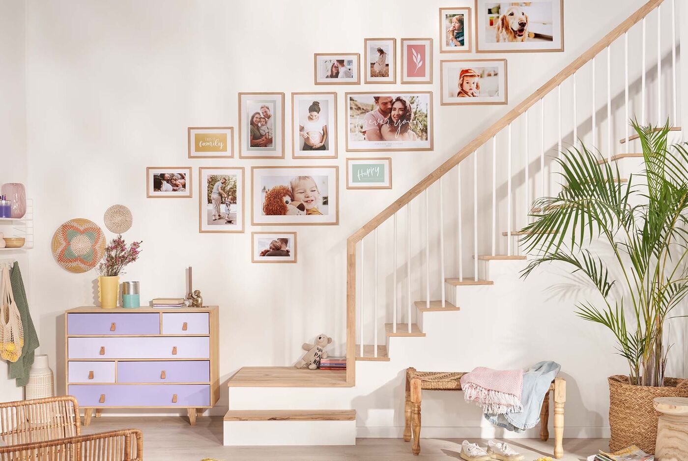 Helle Treppe mit bunten Rahmungen und Bildern an der Wand, Holzdetails und eine Pflanze