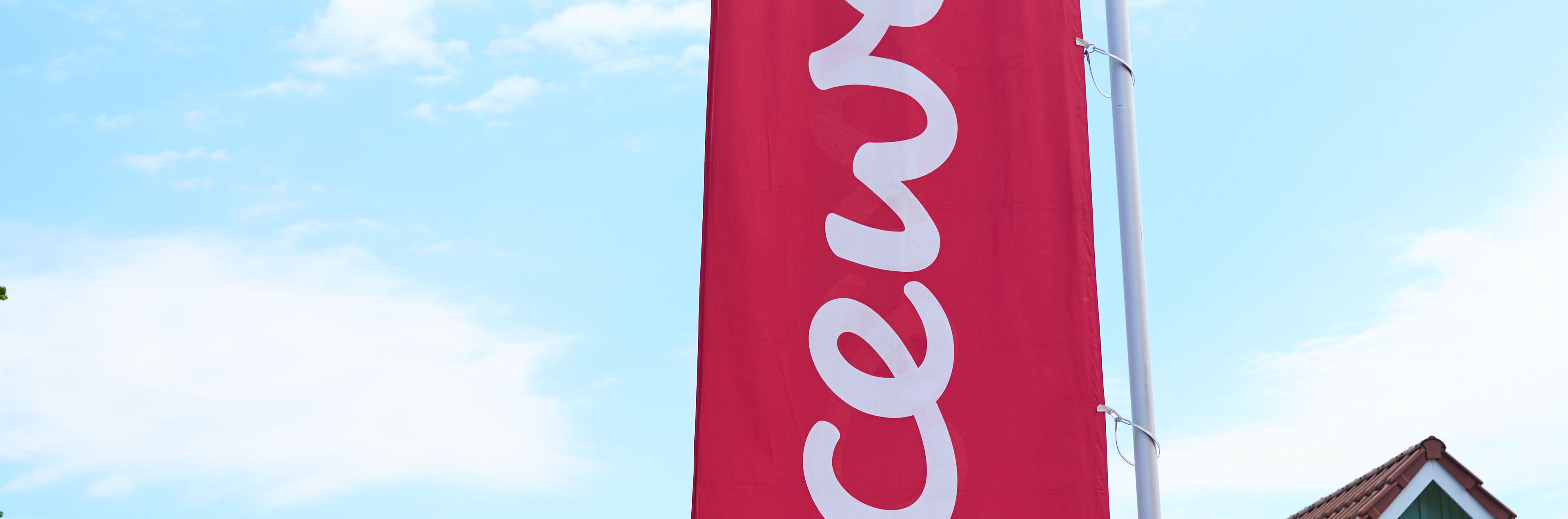 Vor einem Haus weht eine rote Fahne mit dem CEWE Logo.