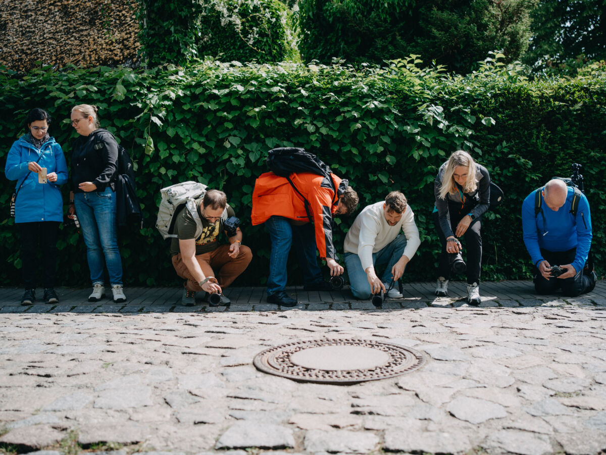 Eine Gruppe von Fotografinnen und Fotografen fotografiert eine Kopfsteinpflasterstraße.