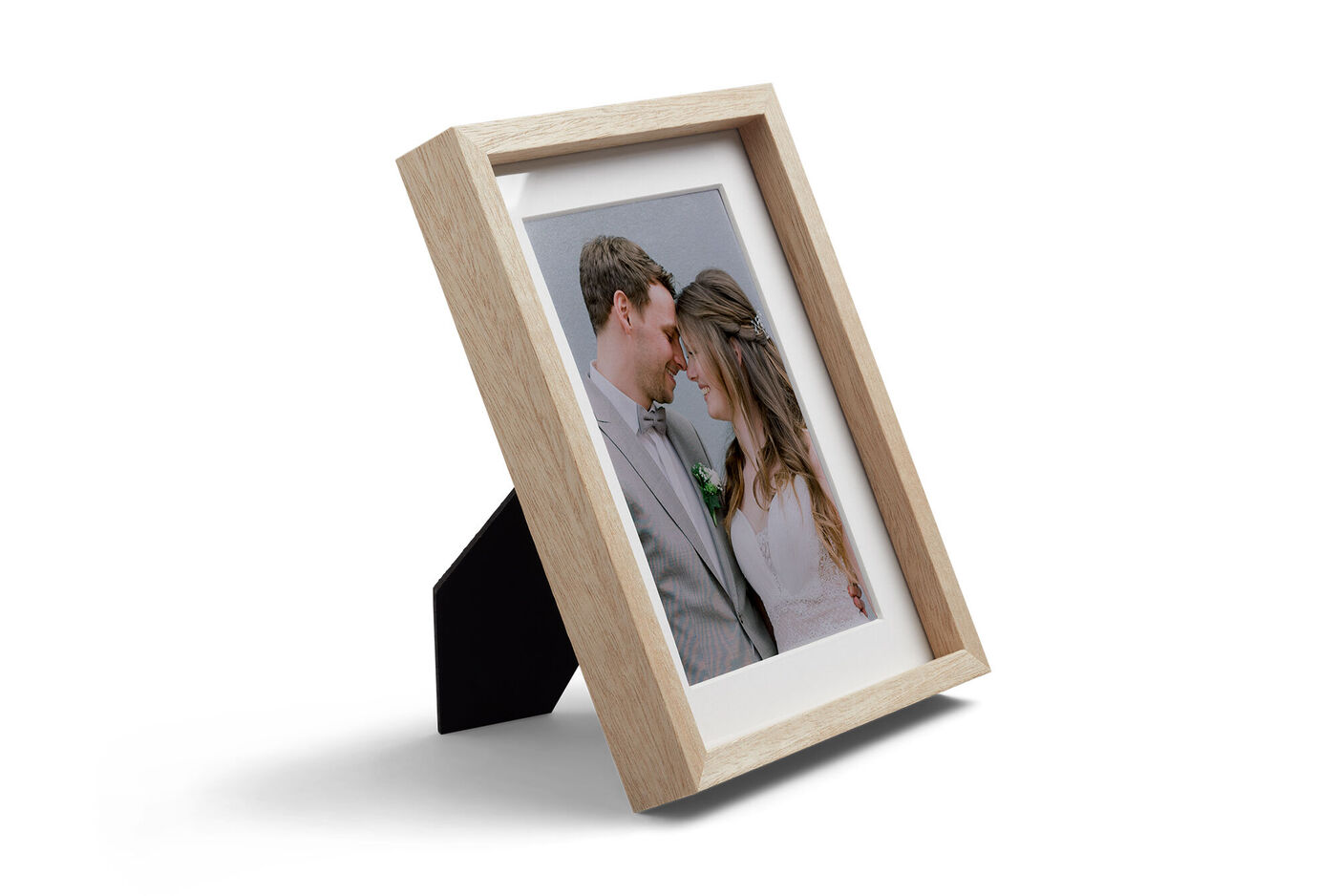 Heller Holzrahmen mit Fotoabzug von verliebtem Paar im Hochzeitsoutfit